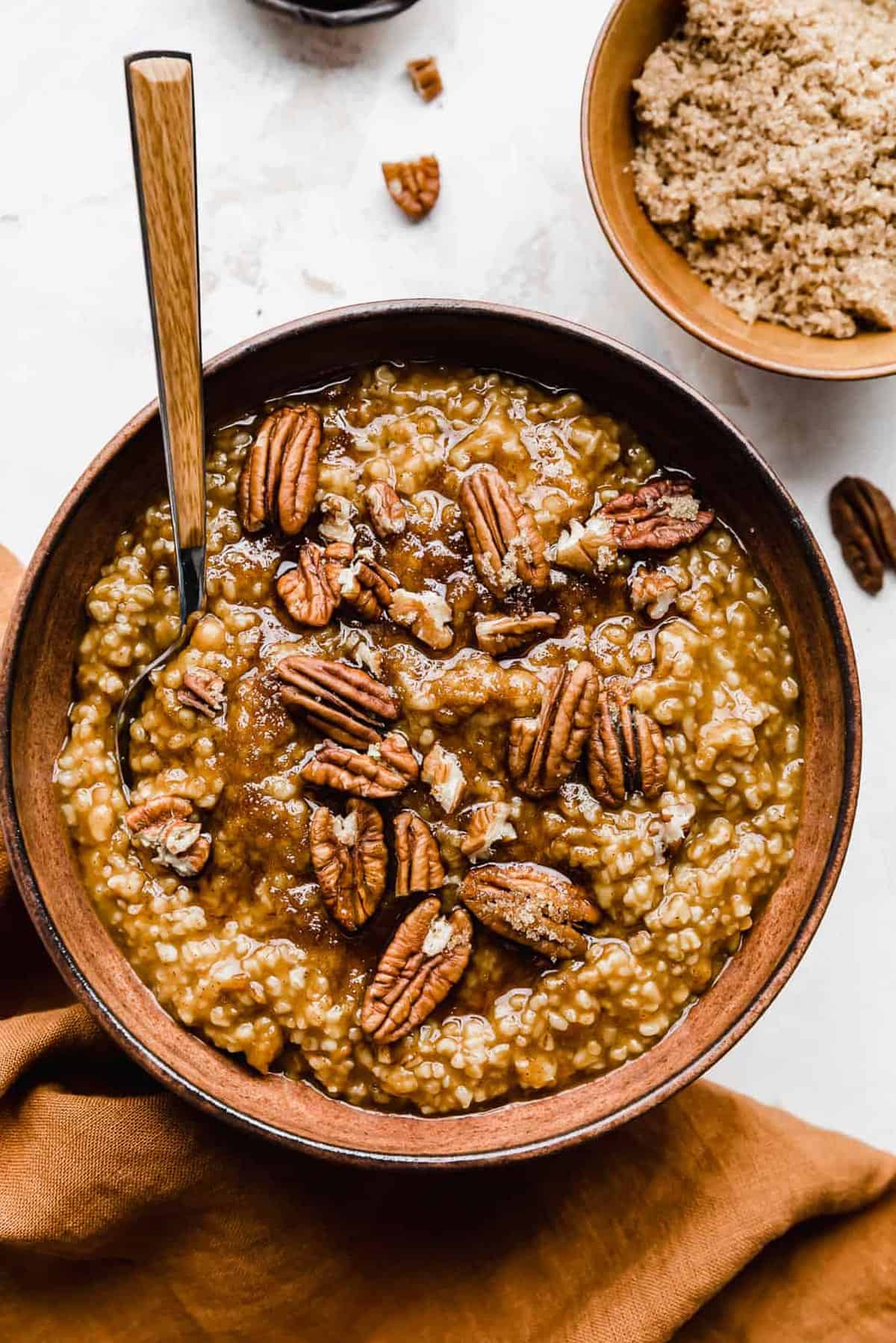 Pumpkin Steel Cut Oats in a brown bowl topped with pecans and brown sugar.