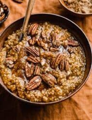 Pumpkin Steel Cut Oats in a brown bowl topped with pecans and brown sugar.