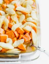 Diced sweet potatoes with sliced apples overtop in a sweet orange sauce.