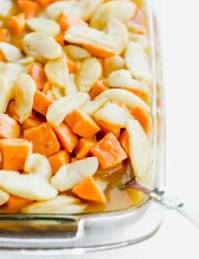 Diced sweet potatoes with sliced apples overtop in a sweet orange sauce.