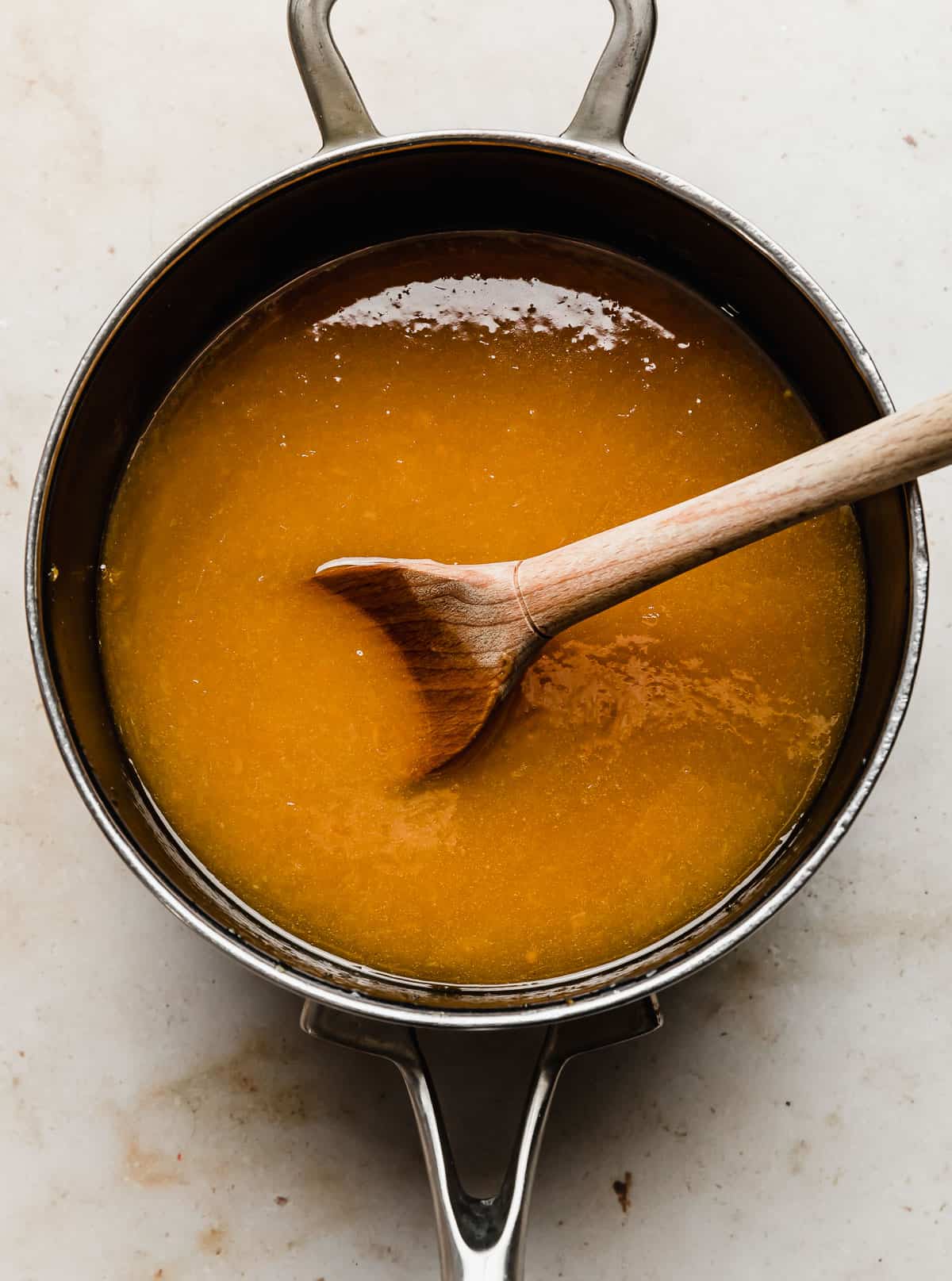 A deep orange colored orange juice candied yams sauce in a saucepan.