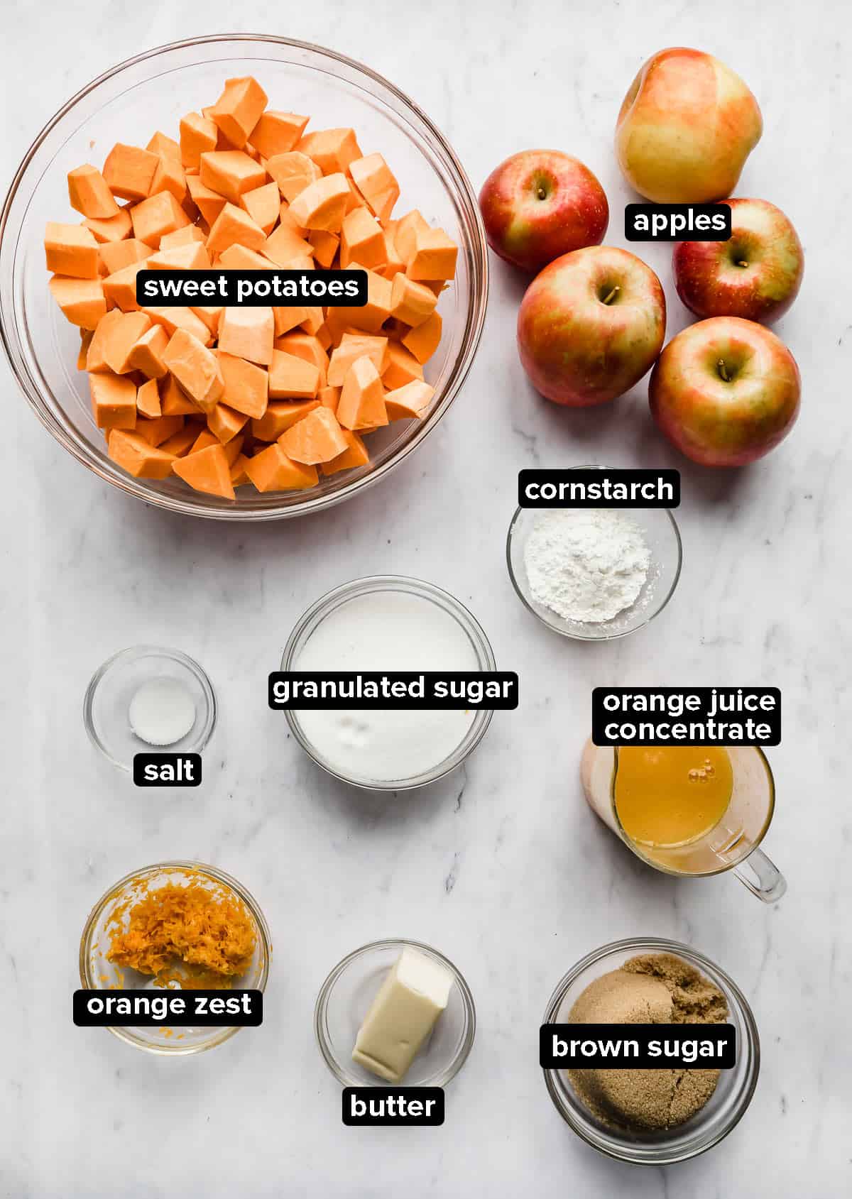 Candied yams ingredients in glass bowls, on a marble background.