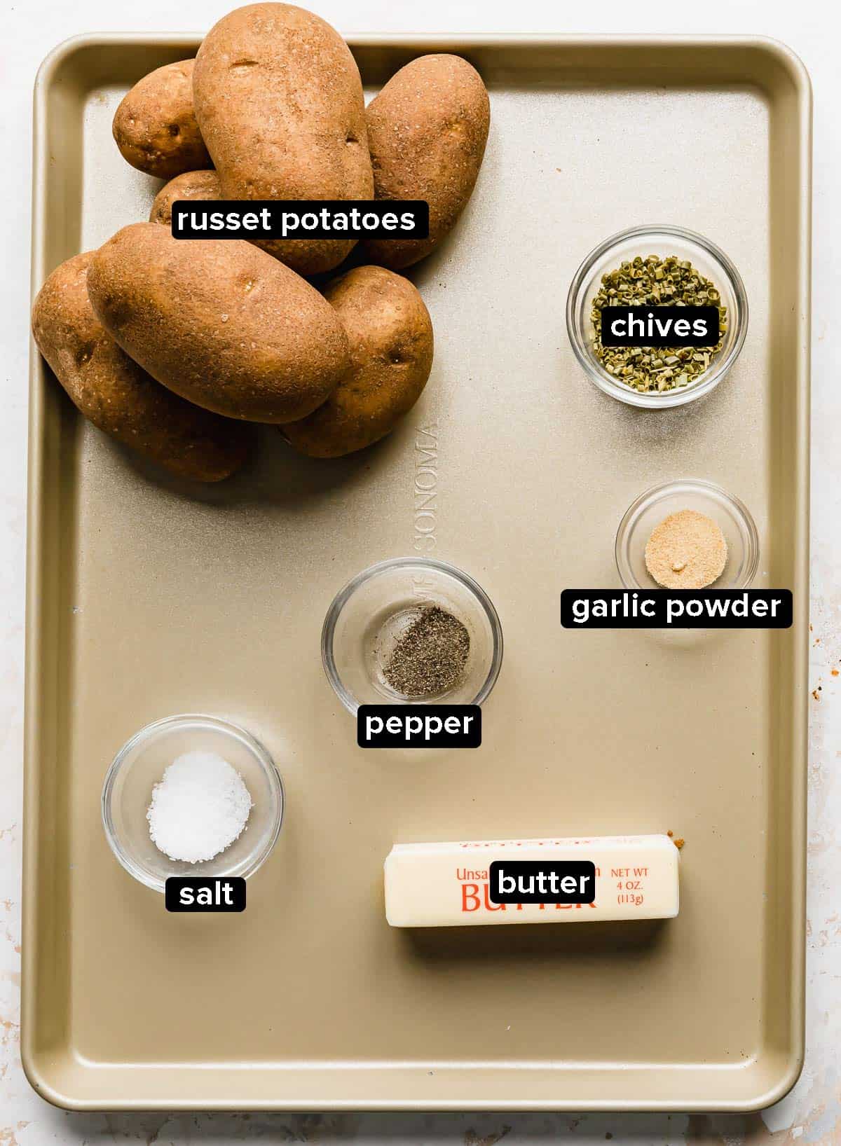 Hasselback Potatoes ingredients on a bronze baking sheet.