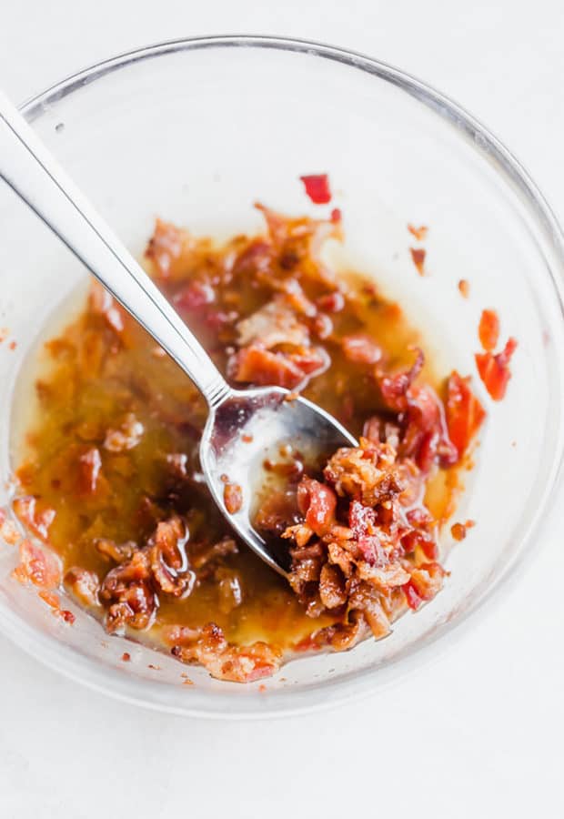 Crumbled bacon in a glass bowl with melted butter and maple syrup.