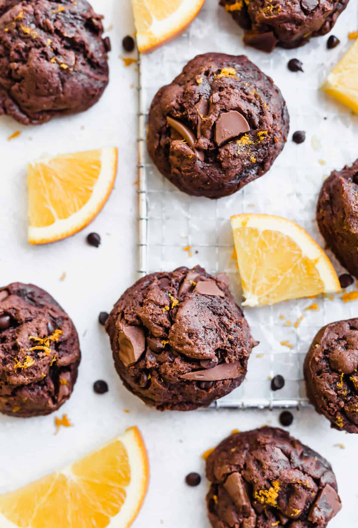 Chocolate Orange Cookies on a white background surrounded by sliced oranges.