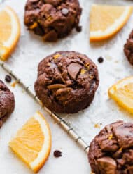 Chocolate Orange Cookies on a wire rack surrounded by fresh orange slices.
