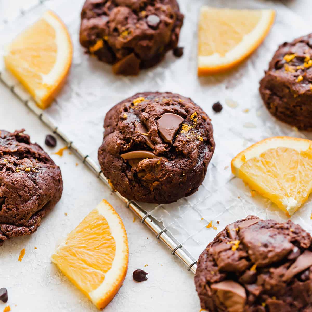 Chocolate Orange Cookies on a wire rack surrounded by fresh orange slices.