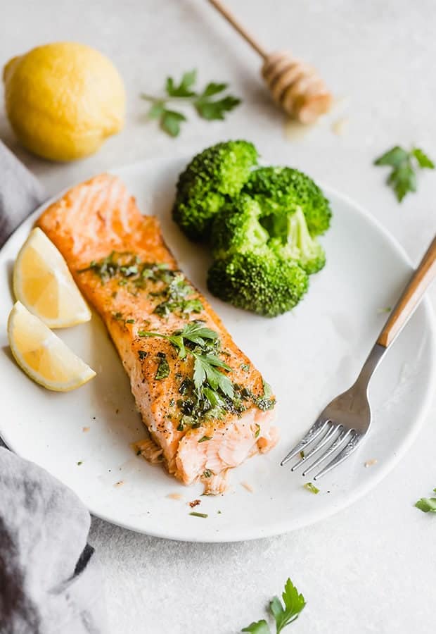 A cooked fillet of salmon topped with a lemon honey glaze, with a serving of broccoli alongside the salmon.