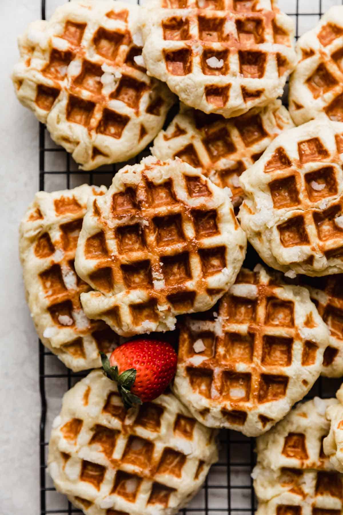 Belgian Liege Waffles stacked on top of one another on a black cooling rack.