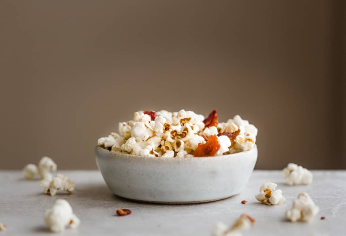A bowl filled with Maple Bacon Popcorn against a light brown background.
