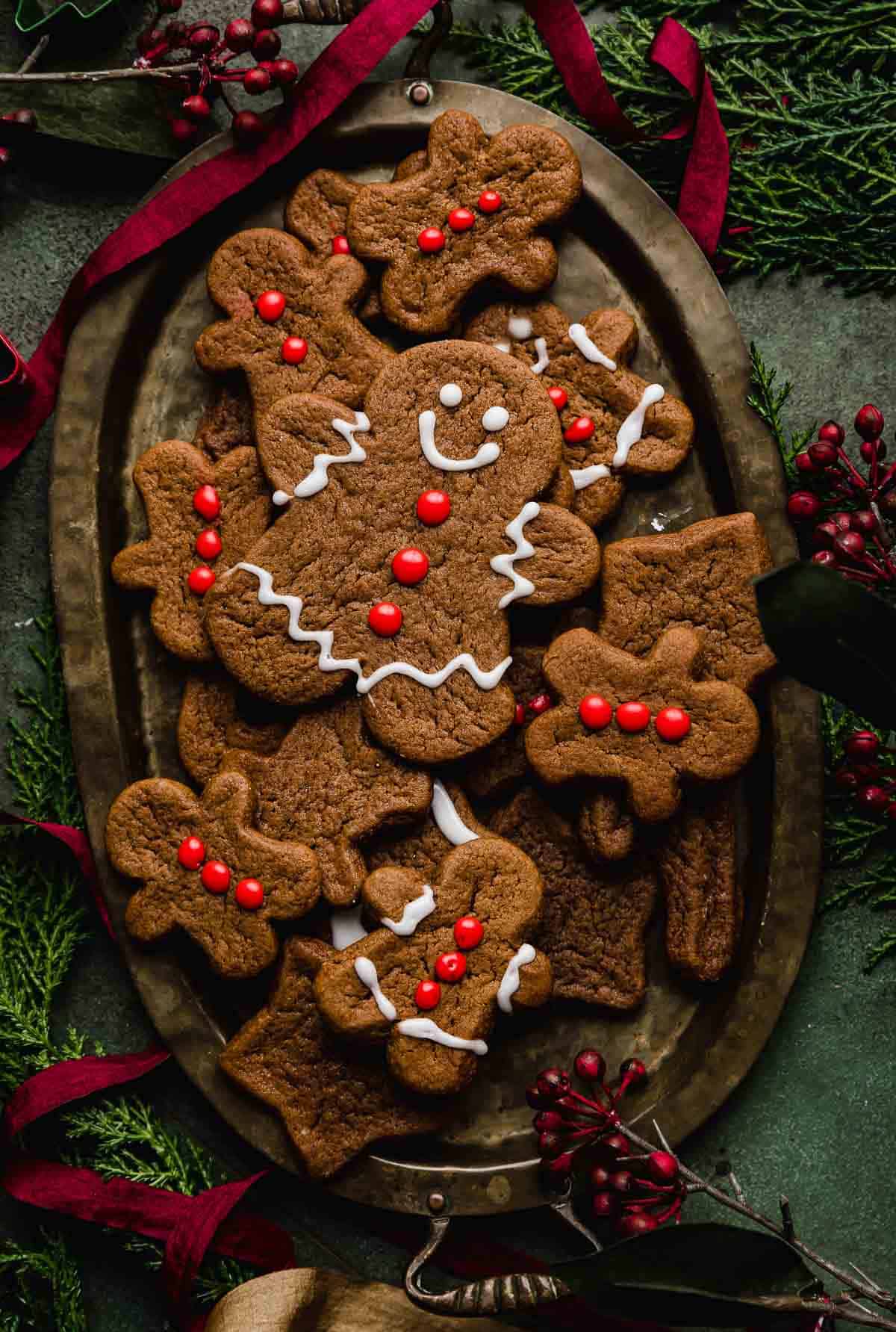 An oval bronze plate with Soft Gingerbread Cookies on it on a dark green background.