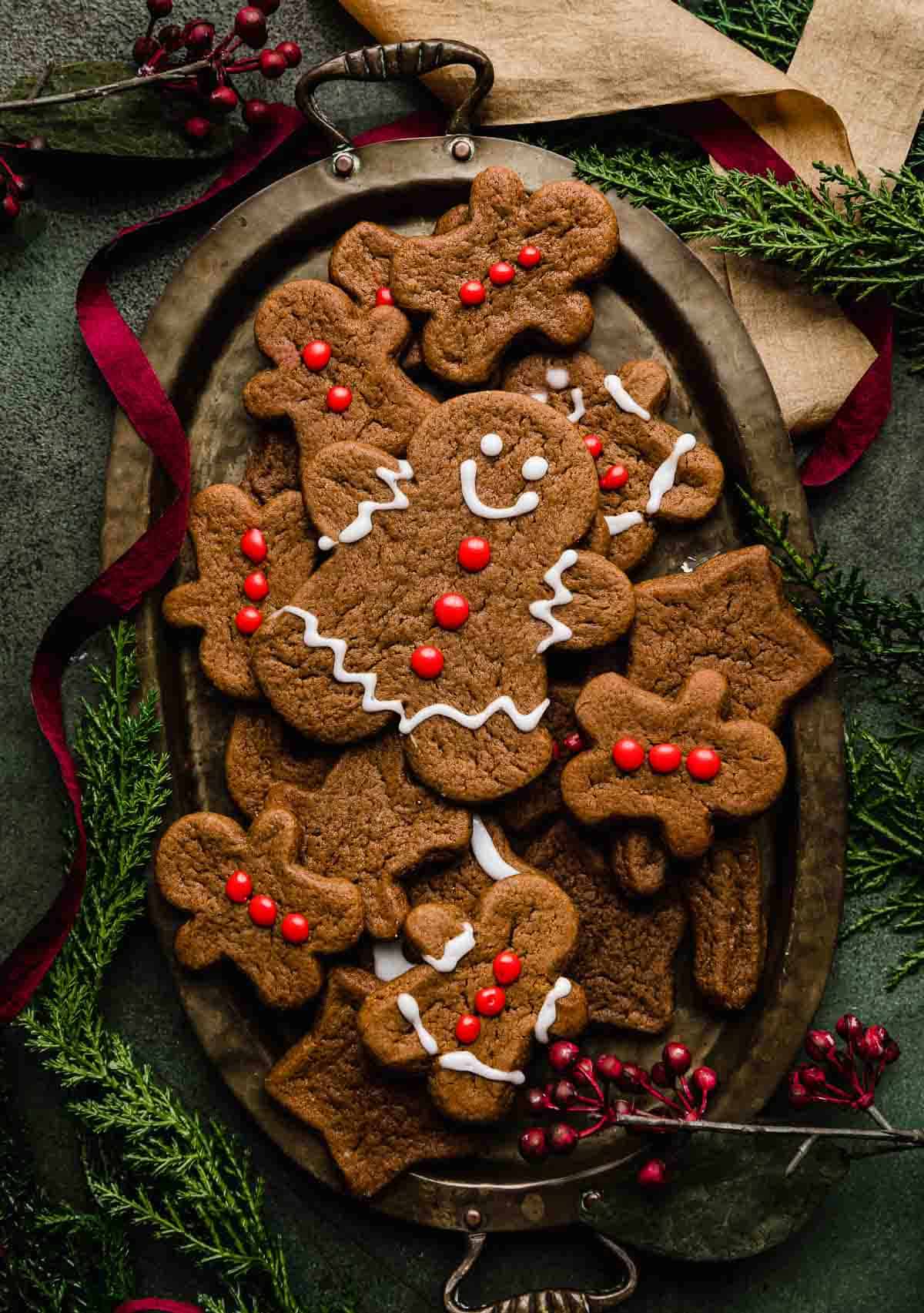 Soft Gingerbread Cookies on an oval plate on a dark green background with red and gold ribbon swirling around the plate.