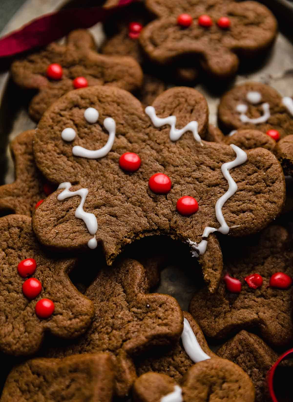 A gingerbread man cookie decorated with white frosting and red frosting buttons.