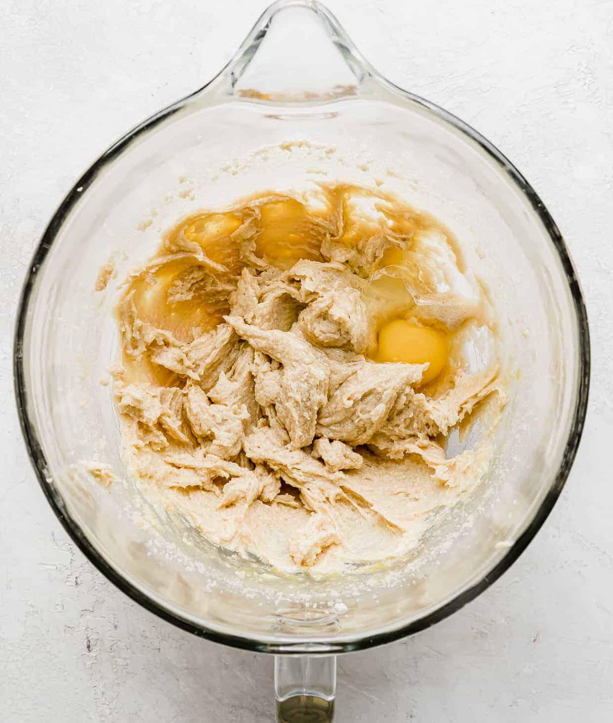 Creamed butter and sugar with cracked eggs in a glass bowl.