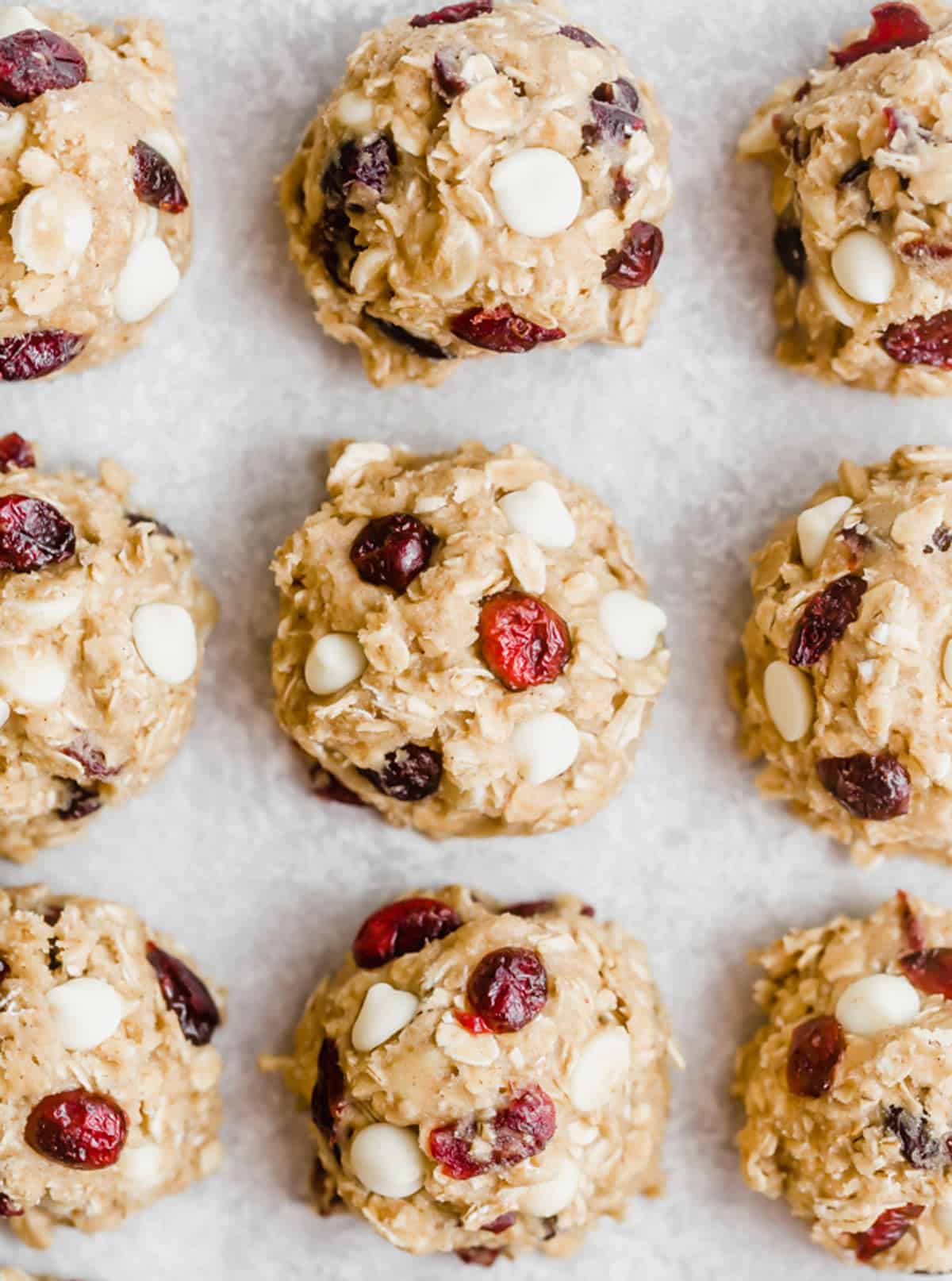 White Chocolate Cranberry Oatmeal Cookie dough balls on a white parchment paper.