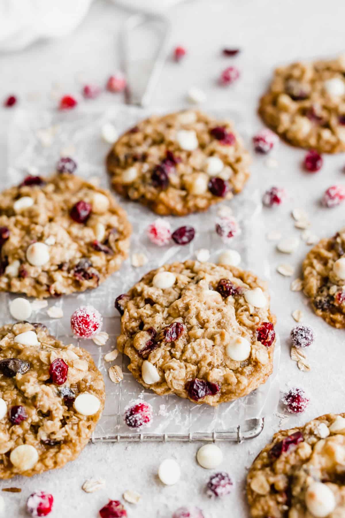 White Chocolate Cranberry Oatmeal Cookies on a wire cooling rack with sugared cranberries scattered around.