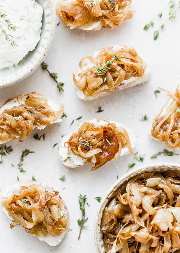 An overhead photograph of crostini topped with caramelized onions, goat cheese, and fresh thyme