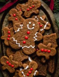 A cute gingerbread man cookie decorated with red frosting buttons and white eyes and smile.