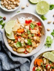A bowl of Massaman curry with cilantro and lime wedges for garnish.