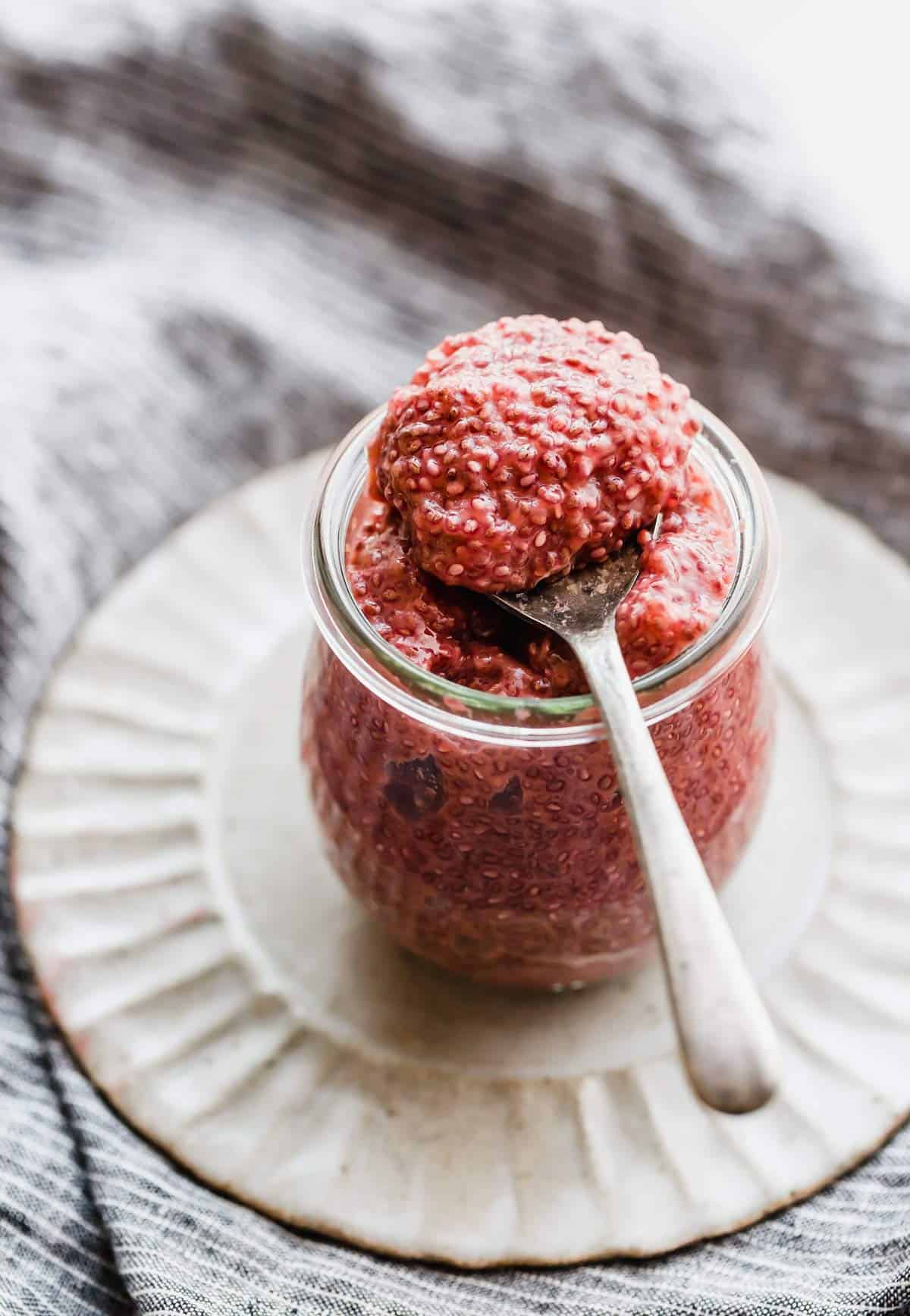A spoon scooping out Blood Orange Chia Pudding from a glass jar.
