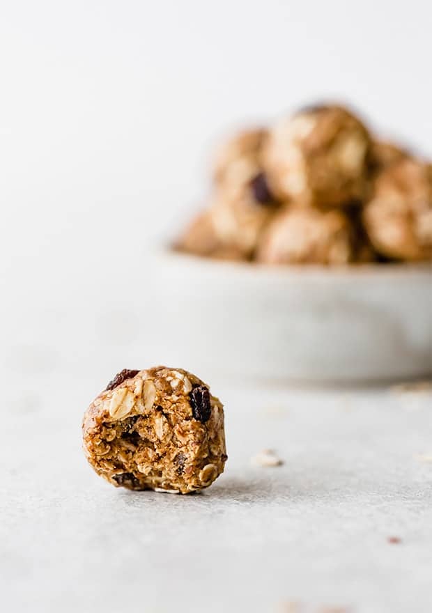 An oatmeal raisin energy bite with a bite taken out of it.