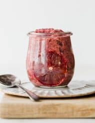 A glass jar filled with Blood Orange Chia Pudding, against a white background.