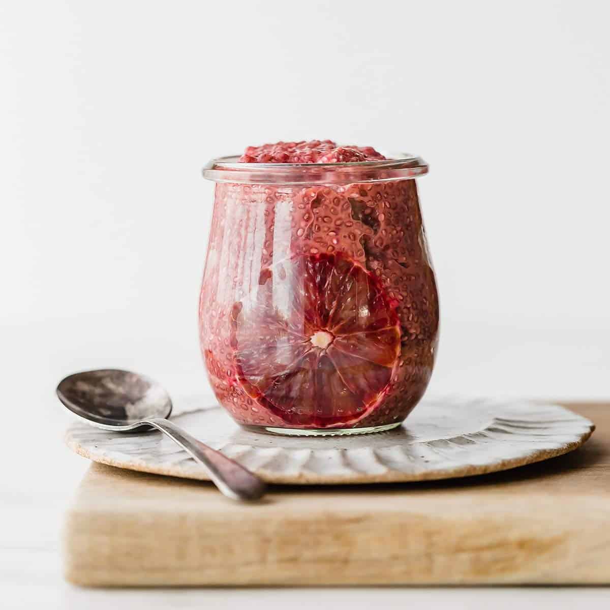 A glass jar filled with Blood Orange Chia Pudding, against a white background.