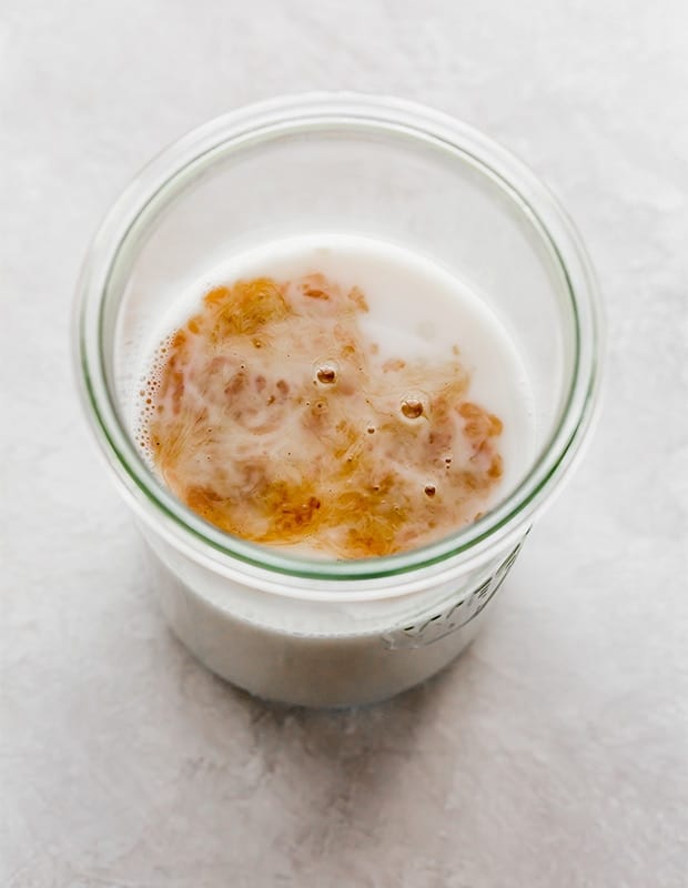 An overhead photo of a large glass jar with almond milk and a splash of vanilla 