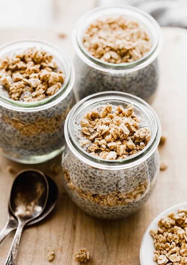 Three glass jars full of chia pudding and topped with granola.
