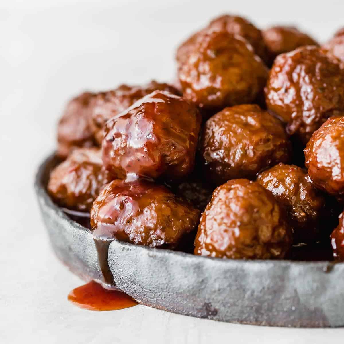 Crock pot Grape Jelly Meatballs on a black plate against a white background.
