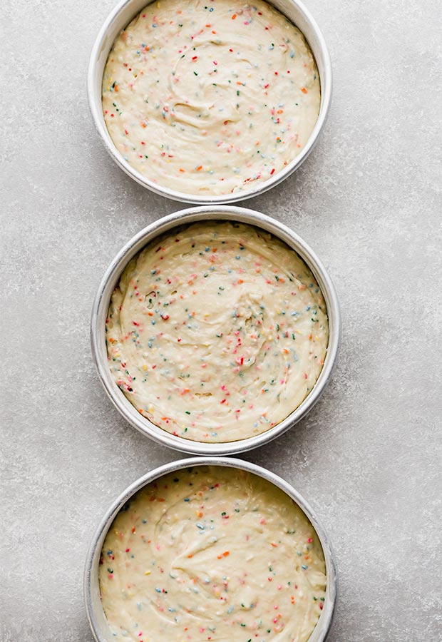 Three eight inch cake pans full of Funfetti Cake batter.