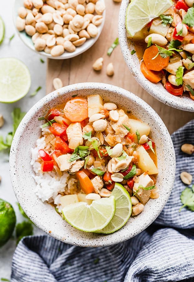 A bowl of Massaman curry with cilantro and lime wedges for garnish.