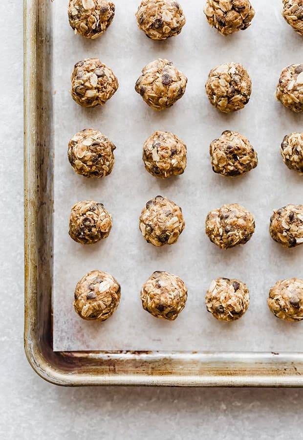 Small no-bake energy bites on a baking sheet lined with parchment paper.