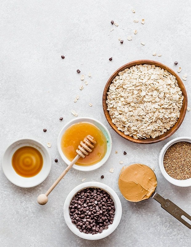 Overhead view of the ingredients needed to make no-bake energy bites; honey, oats, flax seed, peanut butter, chocolate chips, and vanilla. 