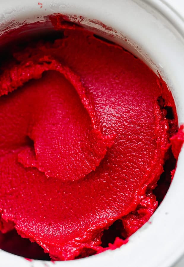 Freshly churned raspberry sorbet in the bowl of an ice cream maker.