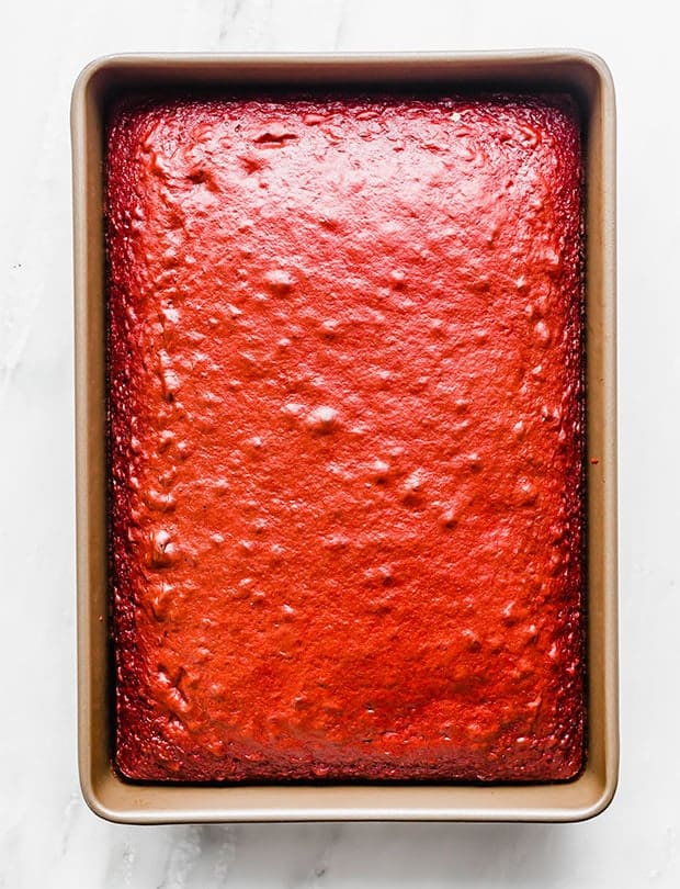 A baked red velvet cake in a 13 x 9 inch pan, in preparation for making red velvet popcorn.