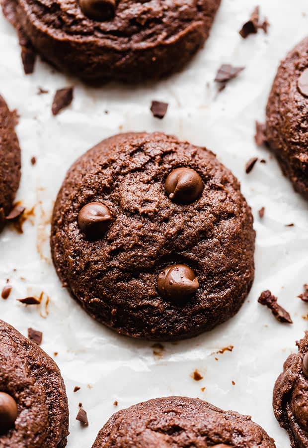 A close up photo of a brownie cookie surrounded by chopped chocolate. 