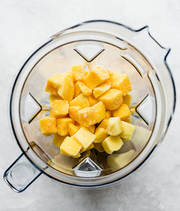 A blender full of frozen mango chunks in preparation for making mango sorbet.