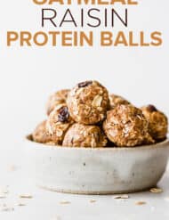 Oatmeal raisin protein balls stacked inside a small ceramic bowl.