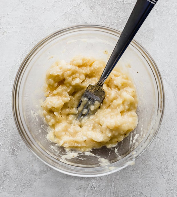Overly ripe, mashed bananas in a glass bowl.