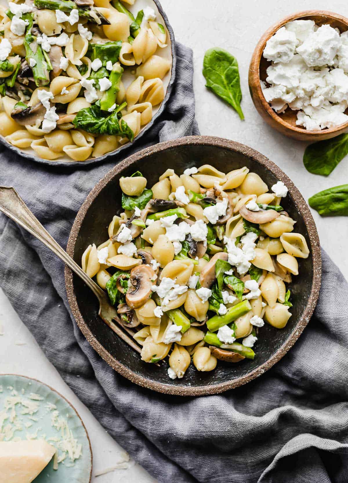 Asparagus Spinach Pasta in a black bowl, with goat cheese over the pasta.