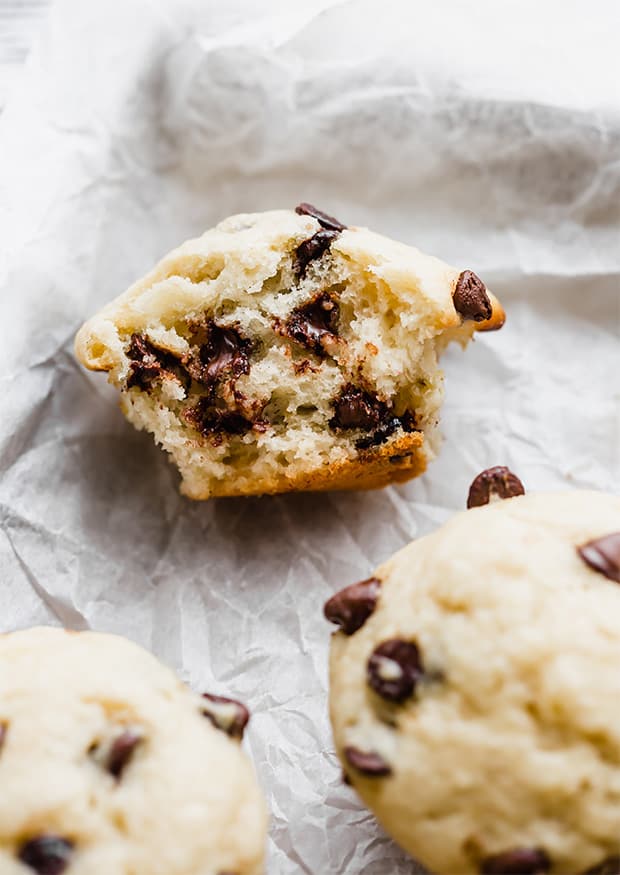 A banana chocolate chip muffin cut in half with melty chocolate chips oozing from the muffin.