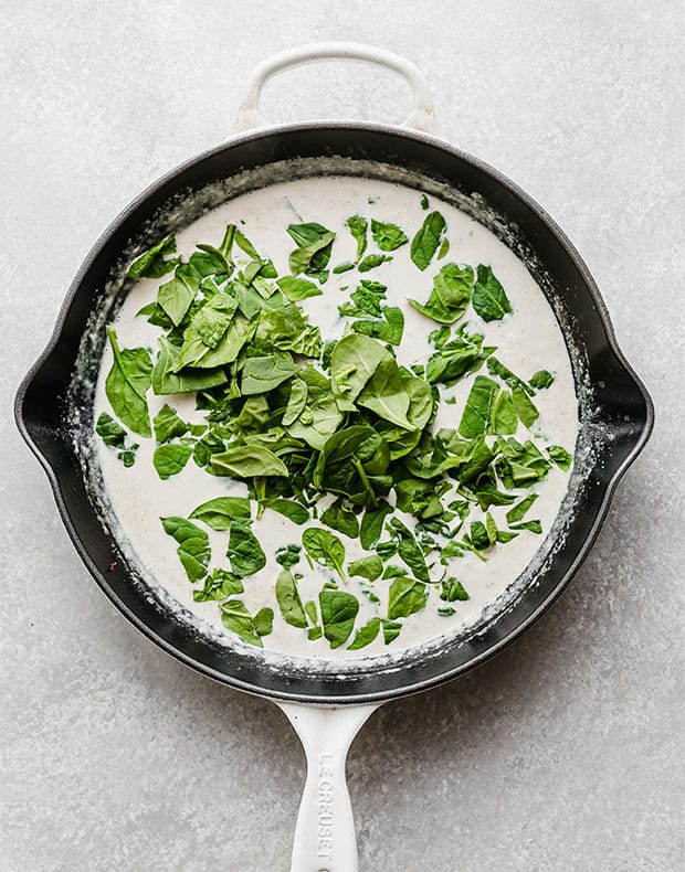 A skillet with a creamy dijon mustard sauce and chopped spinach added on the top.