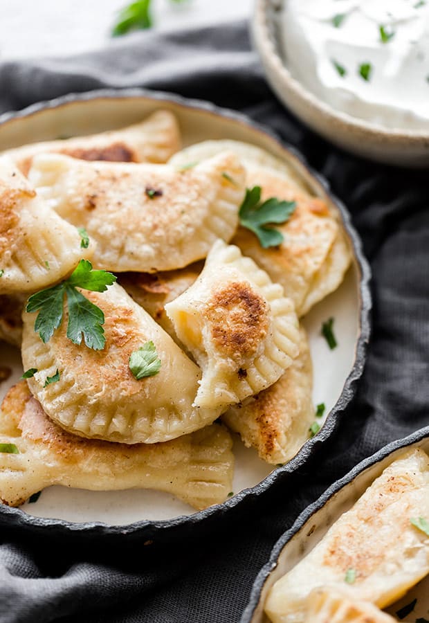A plate of homemade pierogies with a bite taken out of one pierogi. 