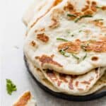 Golden brown cooked Yogurt Naan Bread on a black plate.