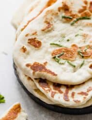 Golden brown cooked Yogurt Naan Bread on a black plate.