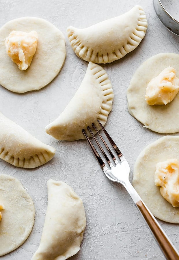 A fork sealing the edges of the filled homemade pierogies.