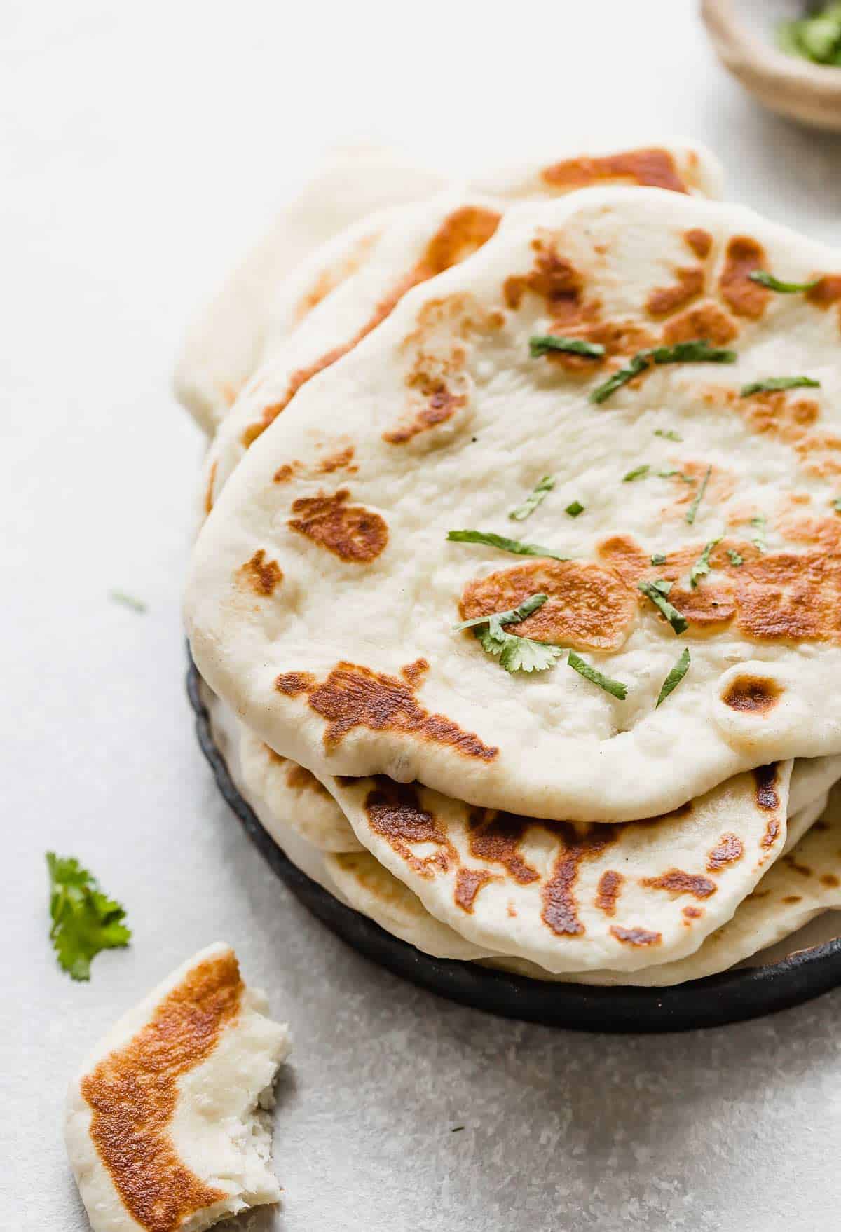 Fluffy naan bread recipe made with yeast and greek yogurt, on a white background.