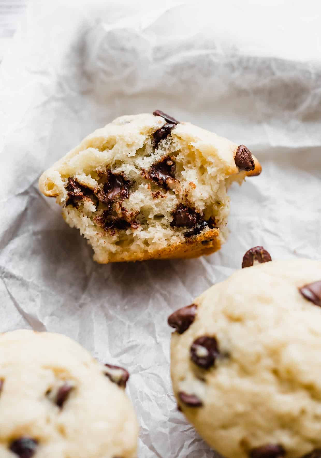 A Buttermilk Banana Chocolate Chip Muffin cut in half on a white parchment paper.