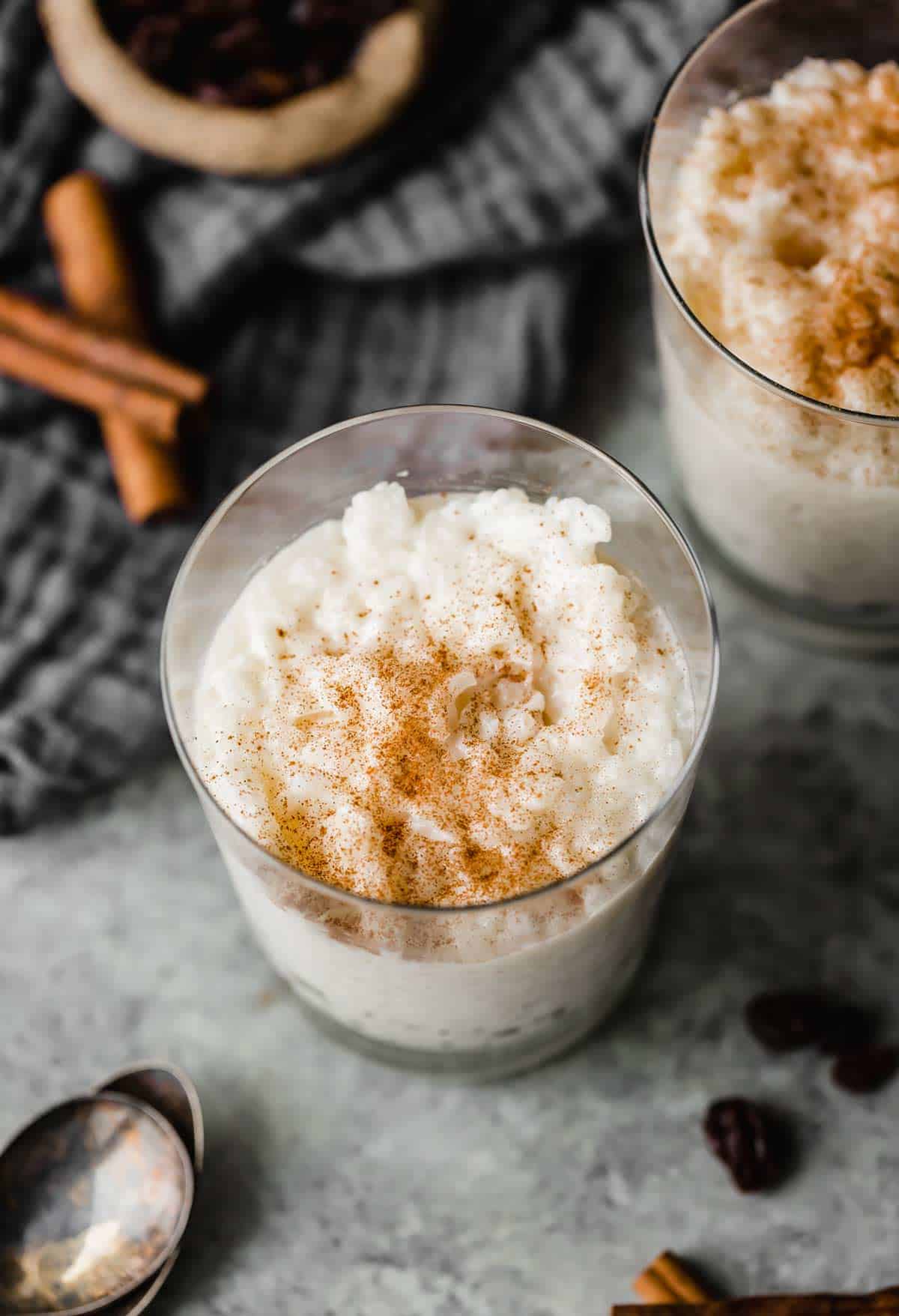 A glass cup filled with Mexican rice pudding that's sprinkled with ground cinnamon.